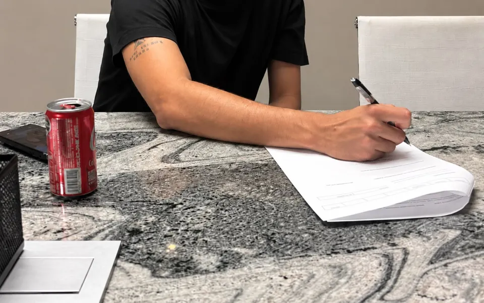 Primer plano de una firma de documentos, sin mostrar rostros.